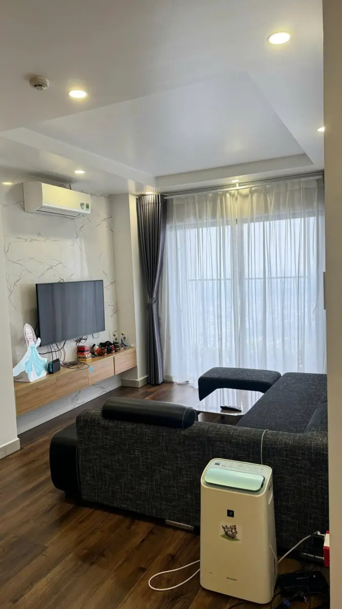 Phòng khách có sofa góc, TV và điều hòa, căn hộ The Minato tầng 24
